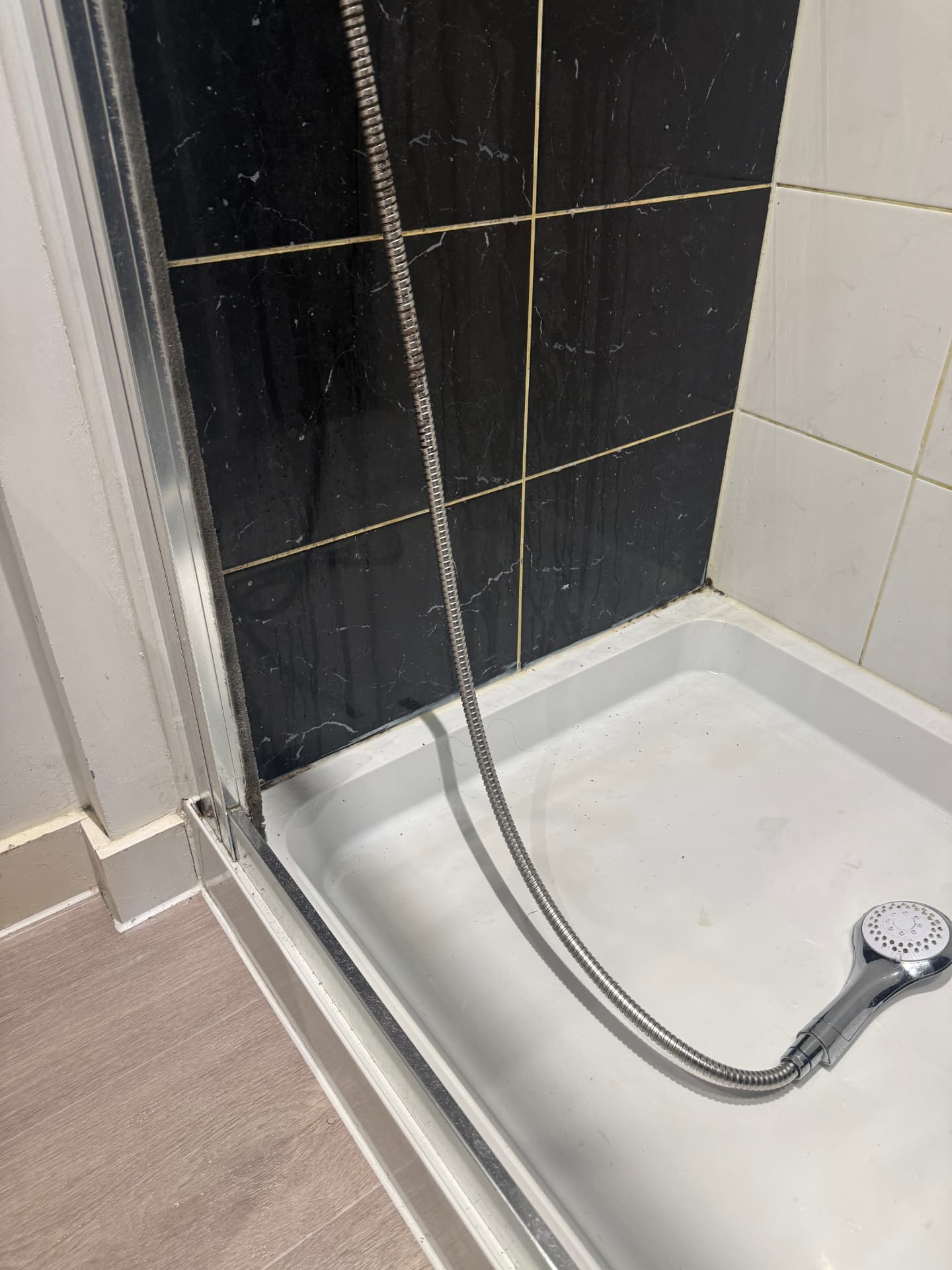Shower enclosure with mould on the seals and grime in the tray before cleaning