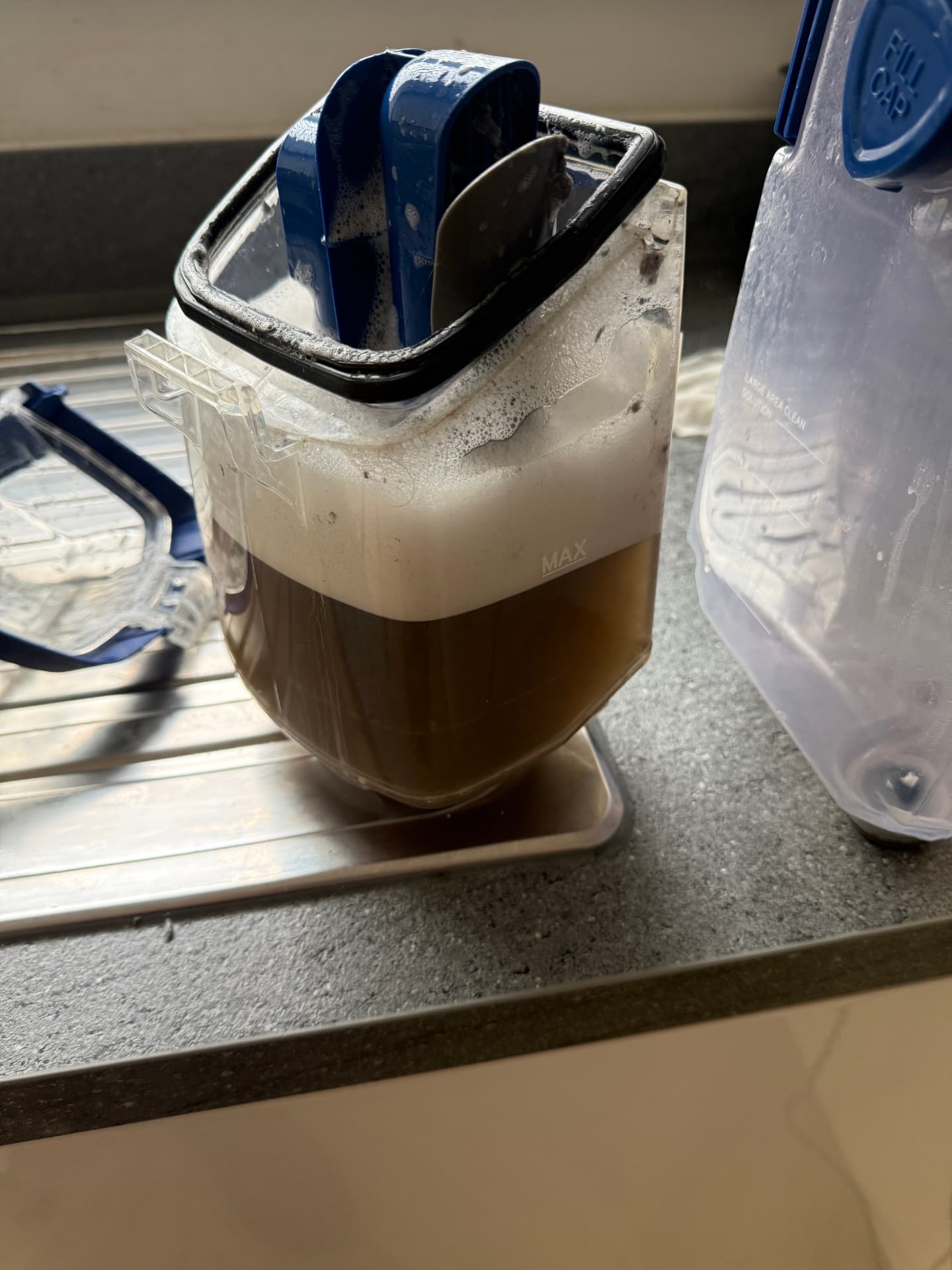 Extraction tank full of dirty brown water removed from a carpet during cleaning