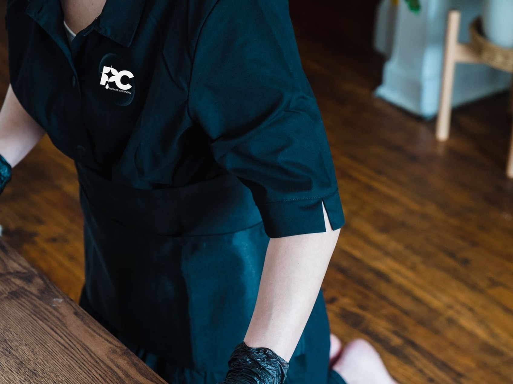 Cleaner in Premier Cleaners branded uniform wiping down a table