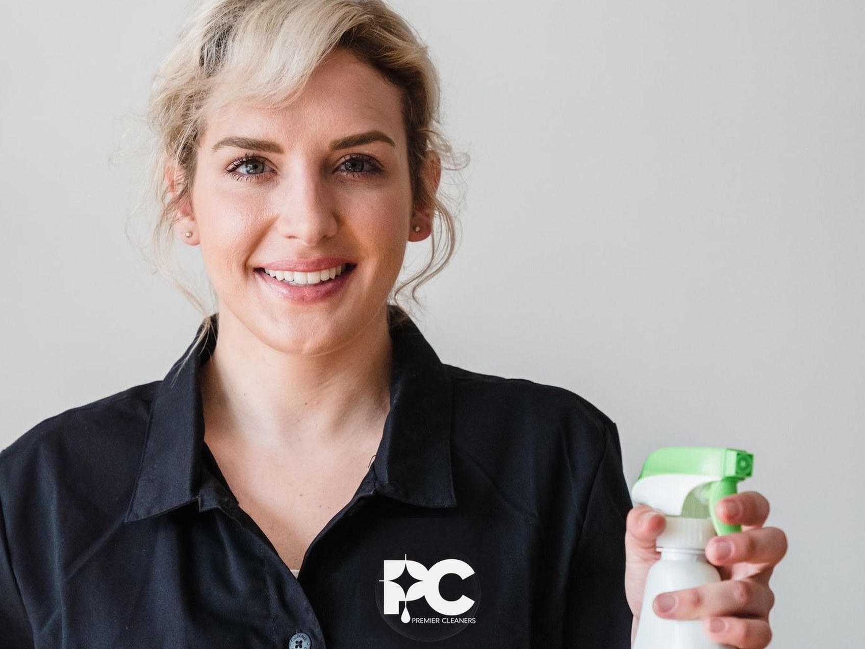 Cleaner in branded Premier Cleaners uniform holding a spray bottle